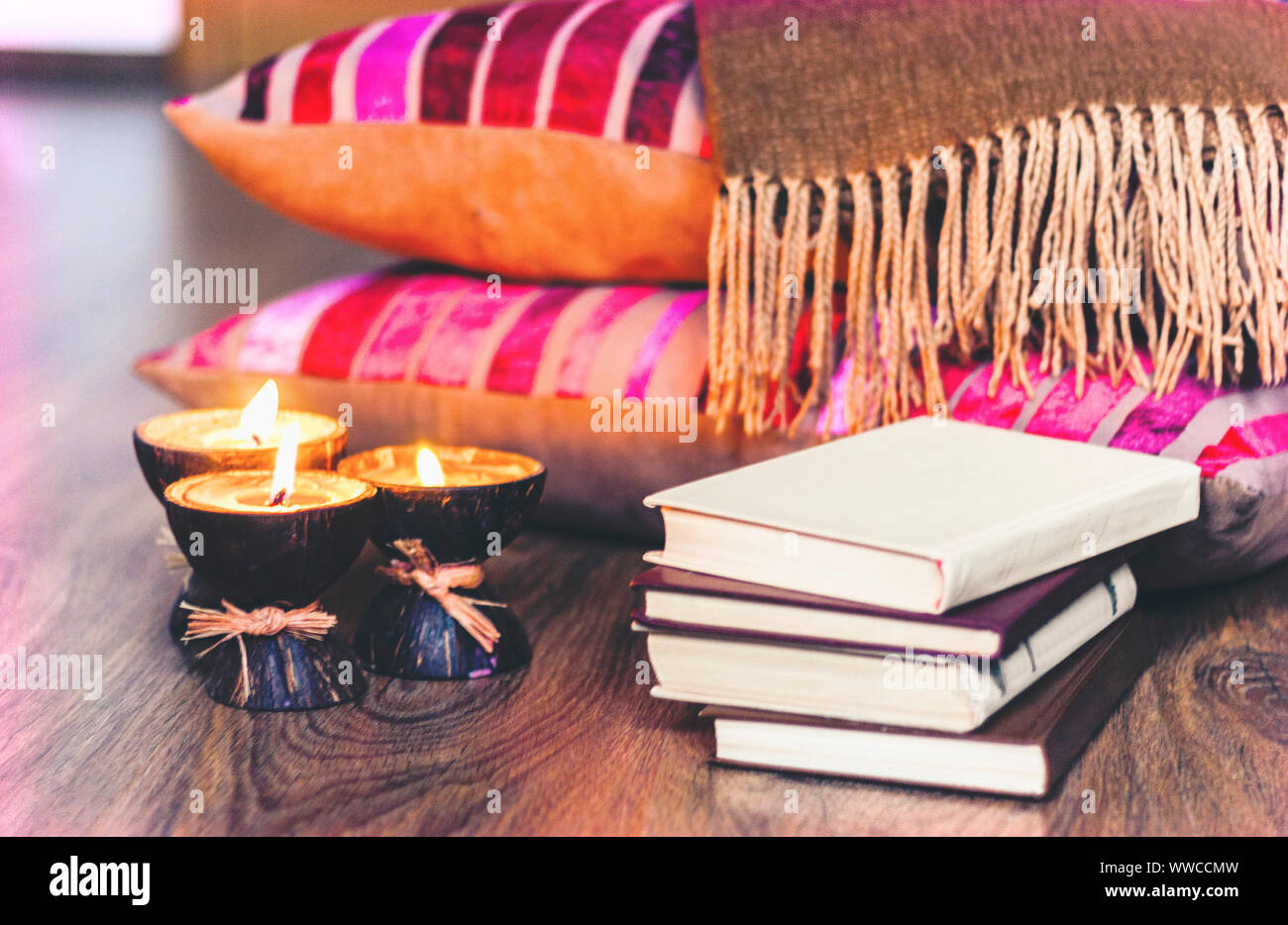 Spa aroma candles burning en coque de noix de coco, plaid et livres, fond intérieur cosy home Banque D'Images