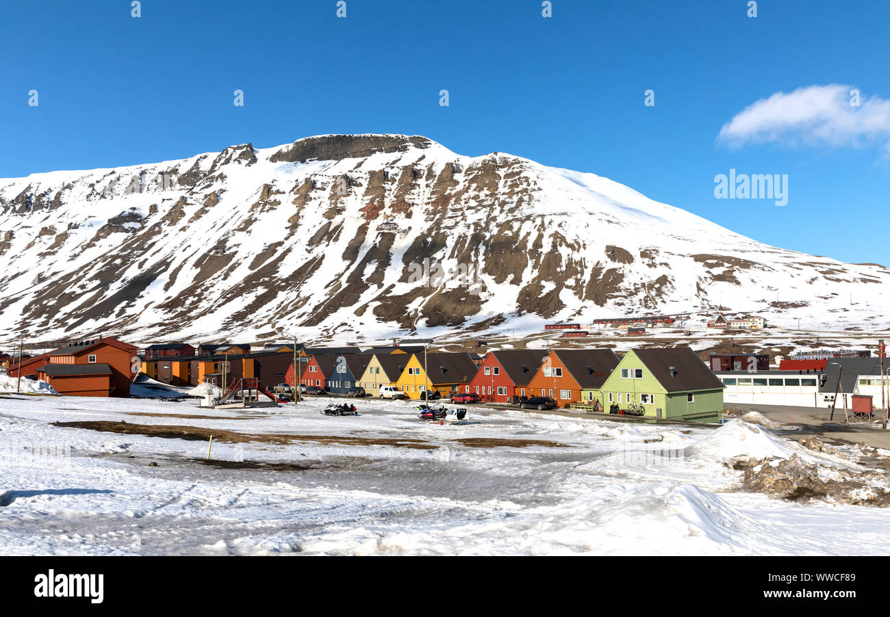 Rangée de maisons chalet coloré à Longyearbyen, Svalbard. Ciel bleu et la montagne de fond avec des motoneiges stationné à l'avant-plan. Banque D'Images