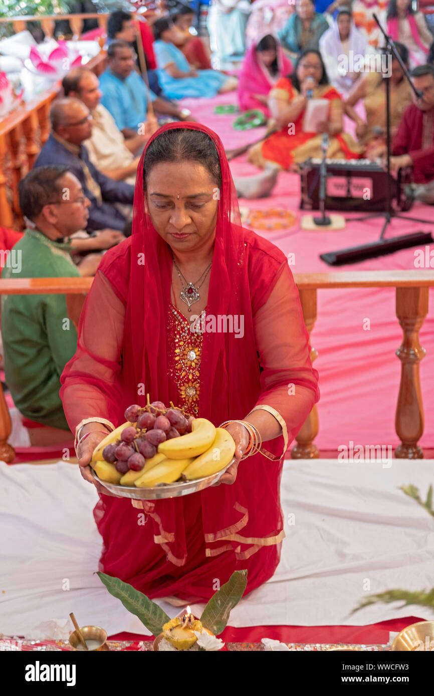 Une pieuse femme hindoue dans un sari propose des fruits pour les déités dans un temple en Jamaïque, Queens, New York. Banque D'Images