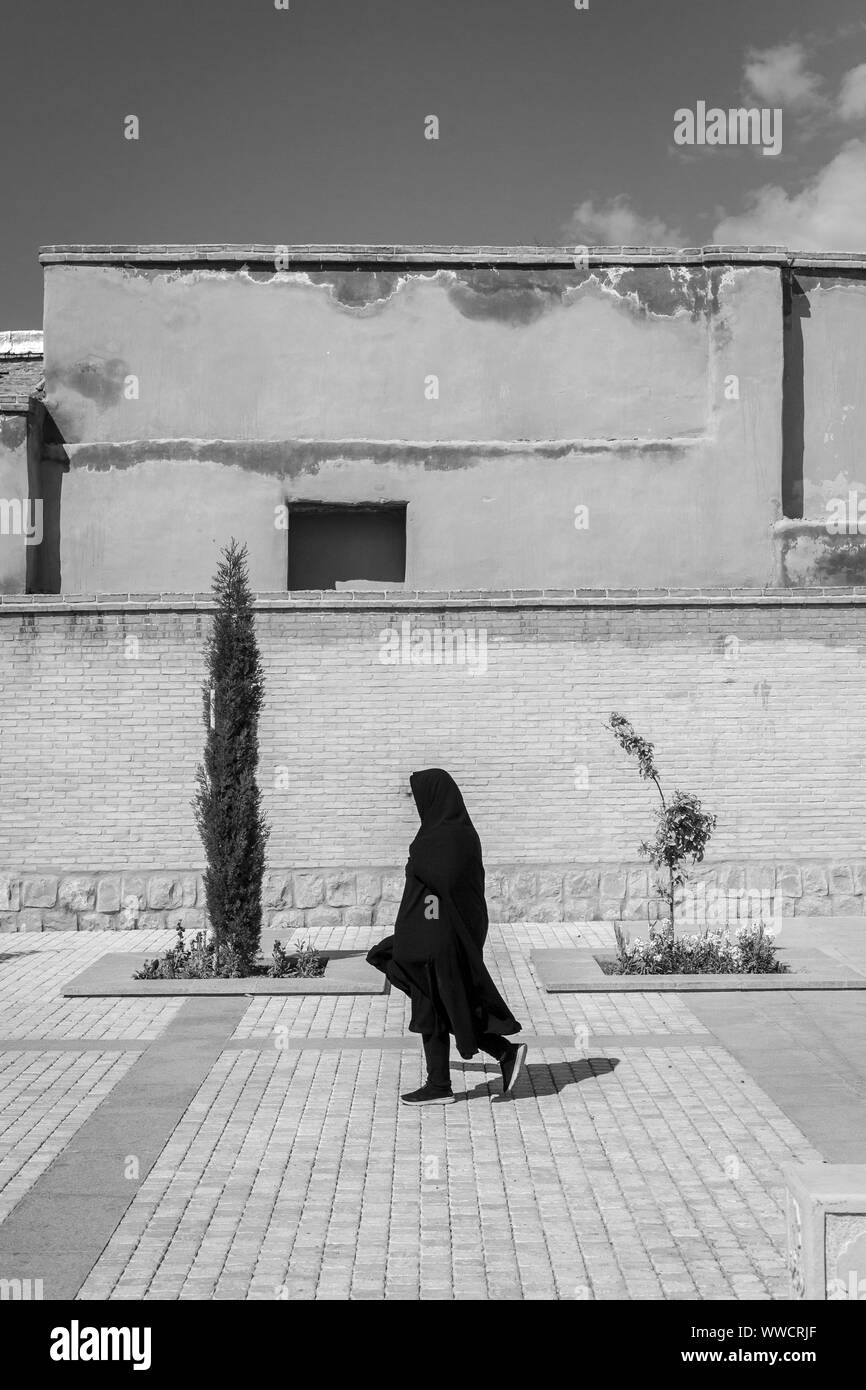 Une femme marche dans une rue en direction de la mosquée à Isfahan, Iran Banque D'Images