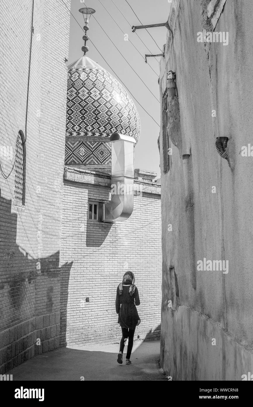 Une femme marche dans une rue en direction de la mosquée à Isfahan, Iran Banque D'Images