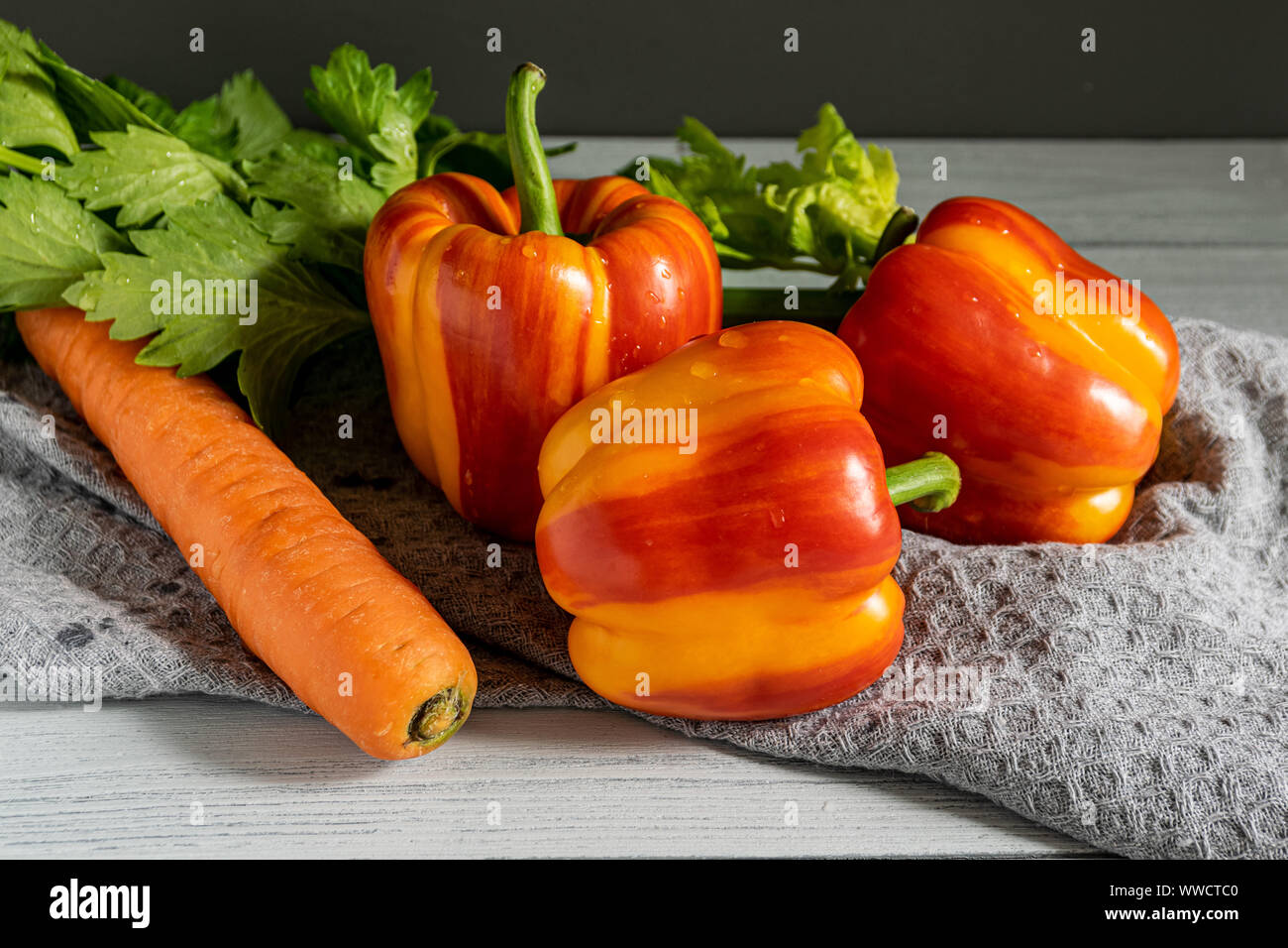 Légumes frais sur un fond clair. orange carotte, deux-tons paprika, tomate rouge et de la salade sur la table de la cuisine. Banque D'Images