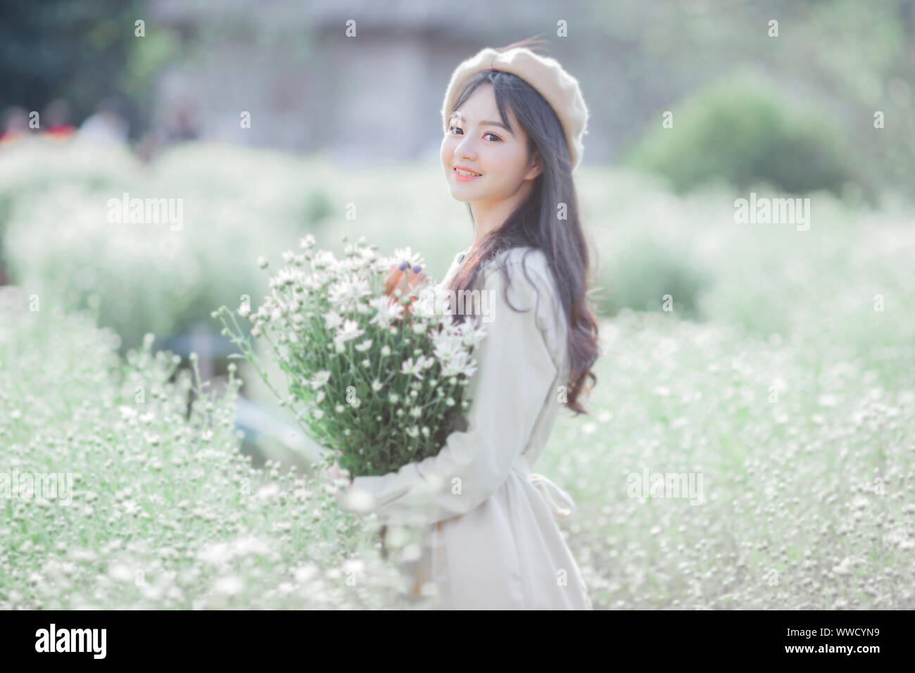 La belle jeune fille à la peau claire et de beaux yeux et la robe maintenant la fleur de chrysanthème était magnifique Banque D'Images