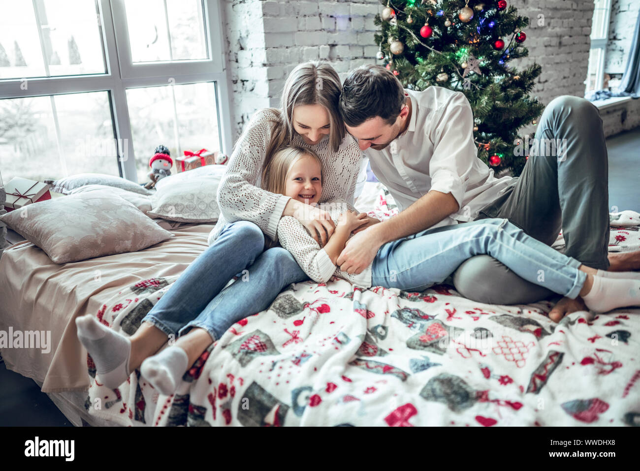 Happy Family wearing lying on bed. Père Mère et enfant s'amusant à l'époque de Noël. Homme, femme et enfant à la maison. Maison de vacances d'hiver et de Noël Banque D'Images