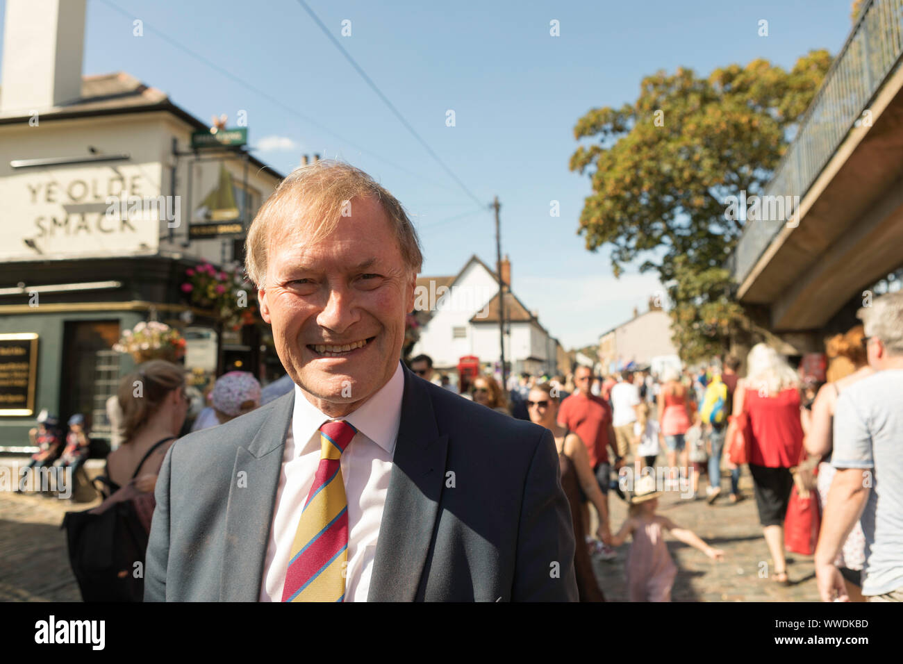 Leigh on Sea, Royaume-Uni. 15 septembre 2019. Sir David Amess à Old Leigh Regatta. En costume et cravate rayée sourit lors de l'événement public animé à Leigh-on-Sea. Les familles et les enfants marchent derrière lui près du pub « The Old Smack », avec des paniers de fleurs suspendus et une ambiance festive. Penelope Barritt/Alamy Live News Banque D'Images