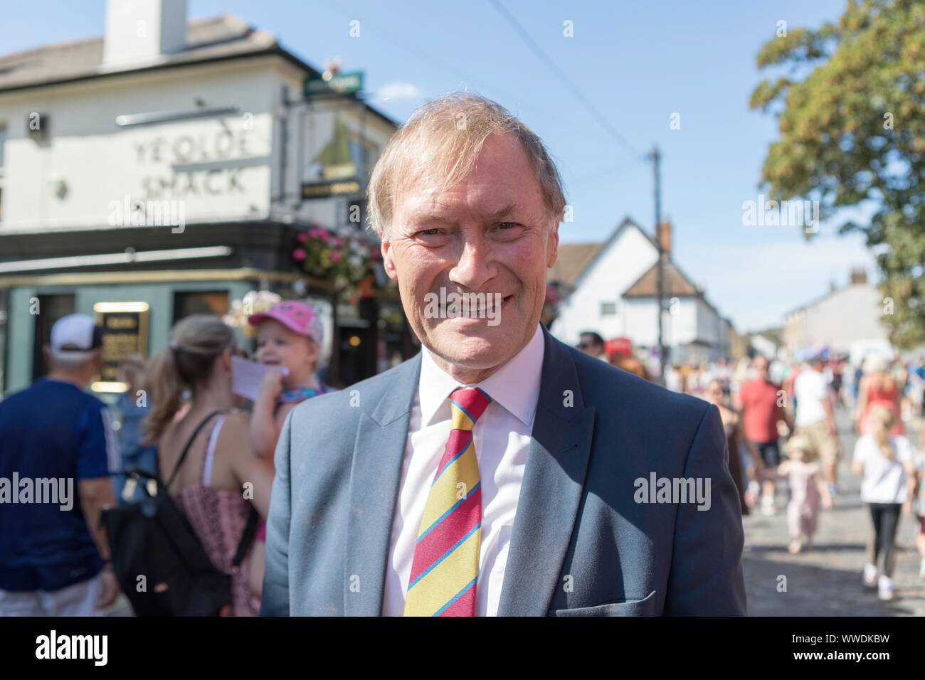 Leigh on Sea, Royaume-Uni. 15 septembre 2019. Sir David Amess à Old Leigh Regatta. En costume et cravate rayée sourit lors de l'événement public animé à Leigh-on-Sea. Les familles et les enfants marchent derrière lui près du pub « The Old Smack », avec des paniers de fleurs suspendus et une ambiance festive. Penelope Barritt/Alamy Live News Banque D'Images