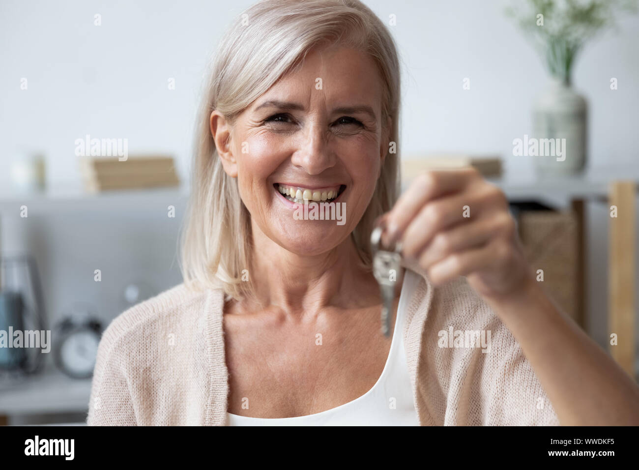 Close up happy woman holding key, looking at camera Banque D'Images