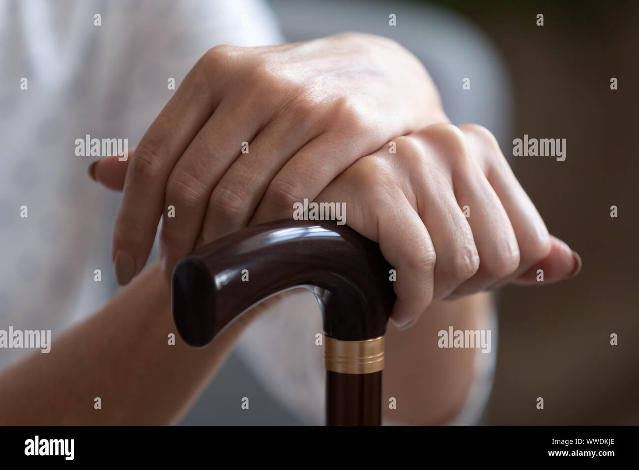 Older woman holding hands sur bâton de marche en bois close up Banque D'Images