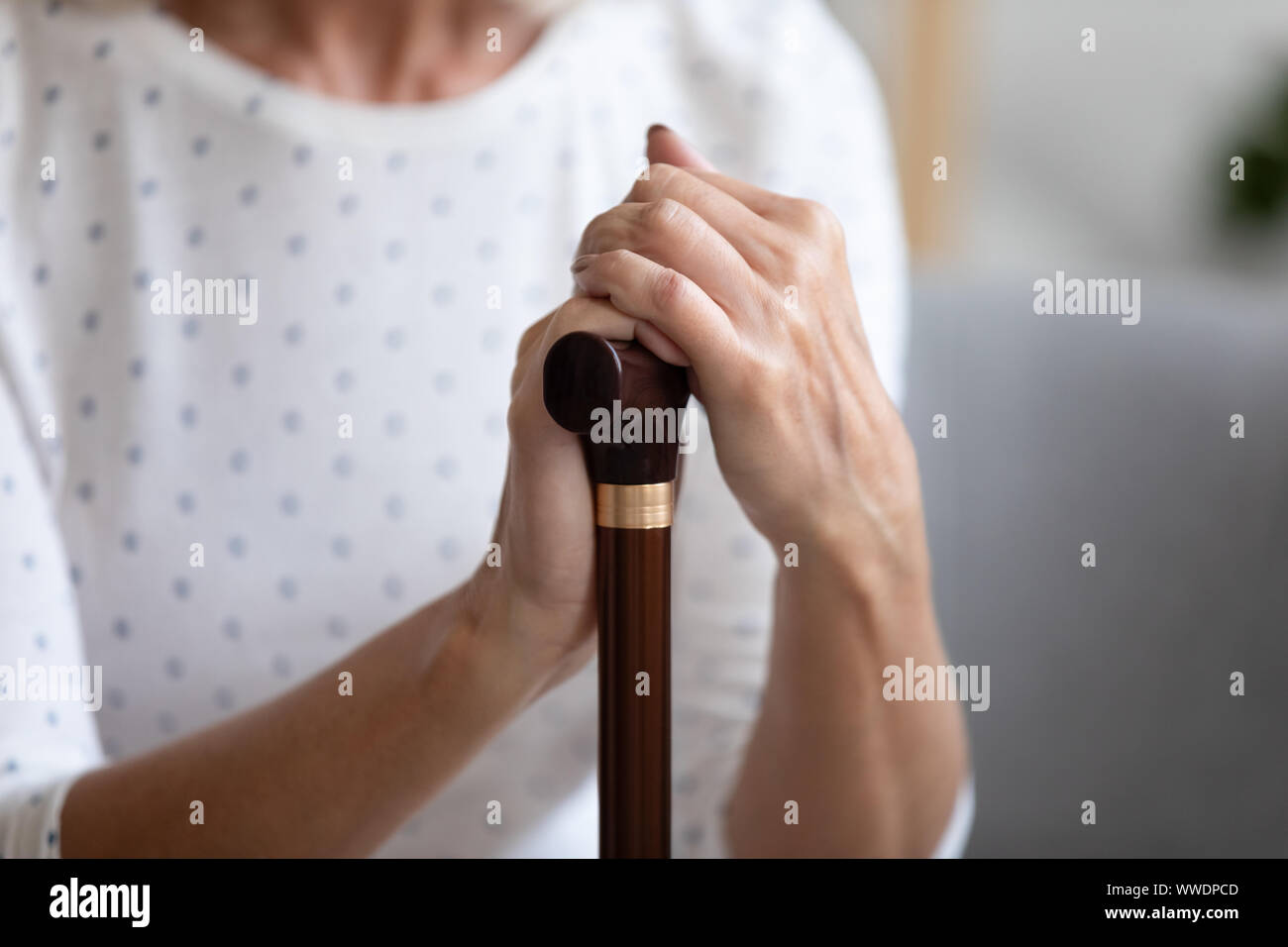 Close up lonely woman holding hands on walking stick Banque D'Images