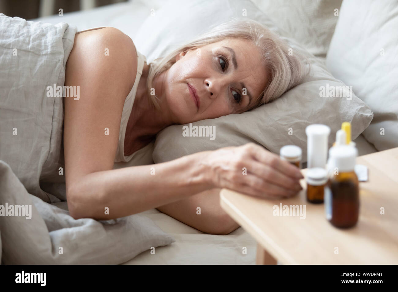 Une mauvaise femme plus prendre les pilules d'une table de chevet close up Banque D'Images