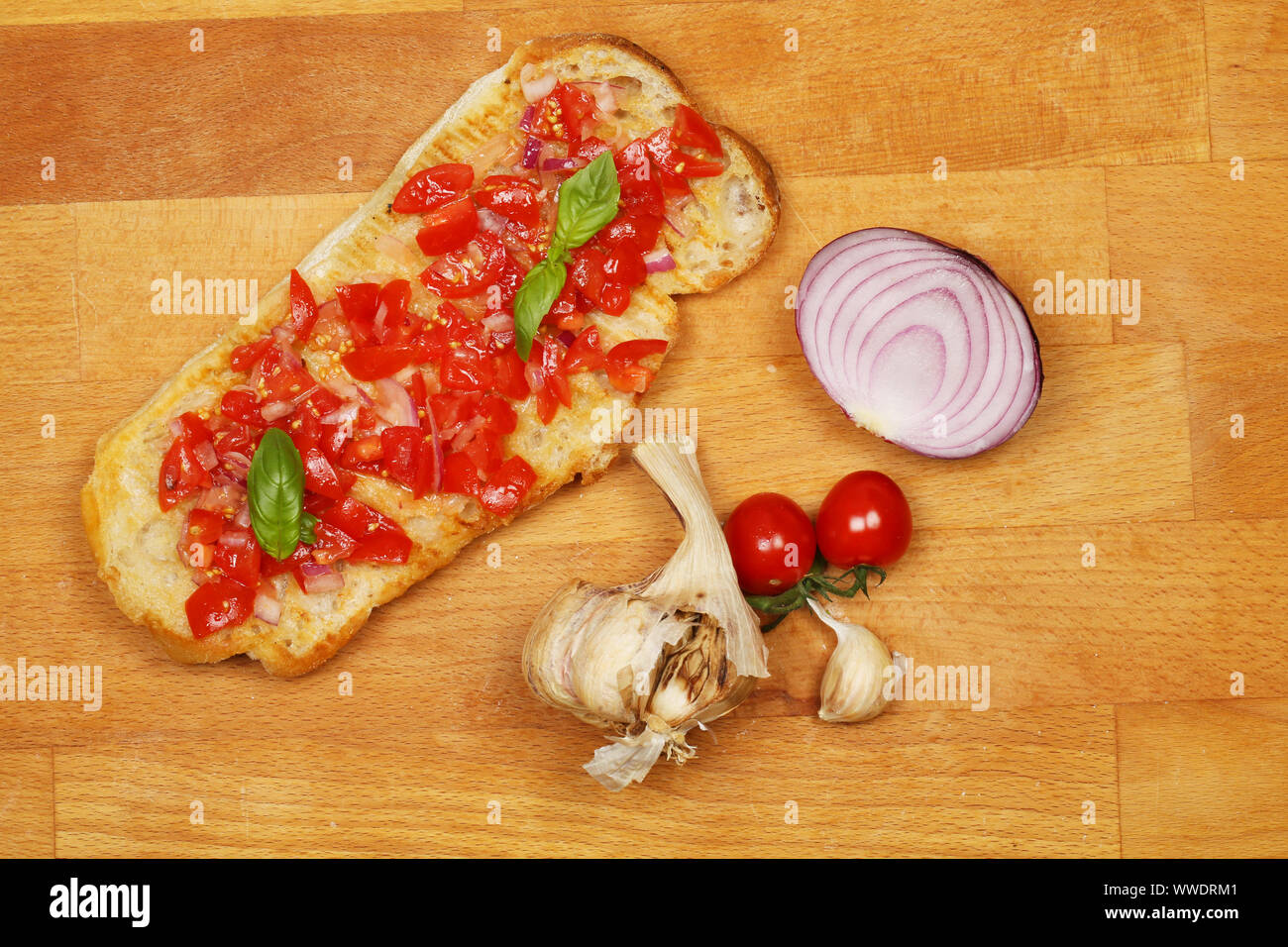 Bruschetta Tomate et oignon rouge et ingrédients sur une planche à découper en bois, vue du dessus Banque D'Images