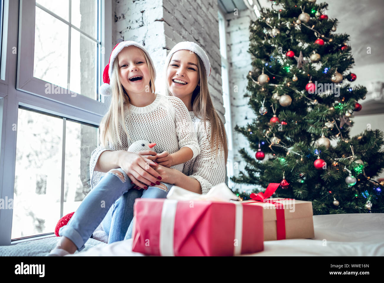 Concept de Noël. Petite fille avec la mère en rouge Santa hat près de l'arbre de Noël. Enfant en attente nouveau concept de famille heureuse année. Banque D'Images