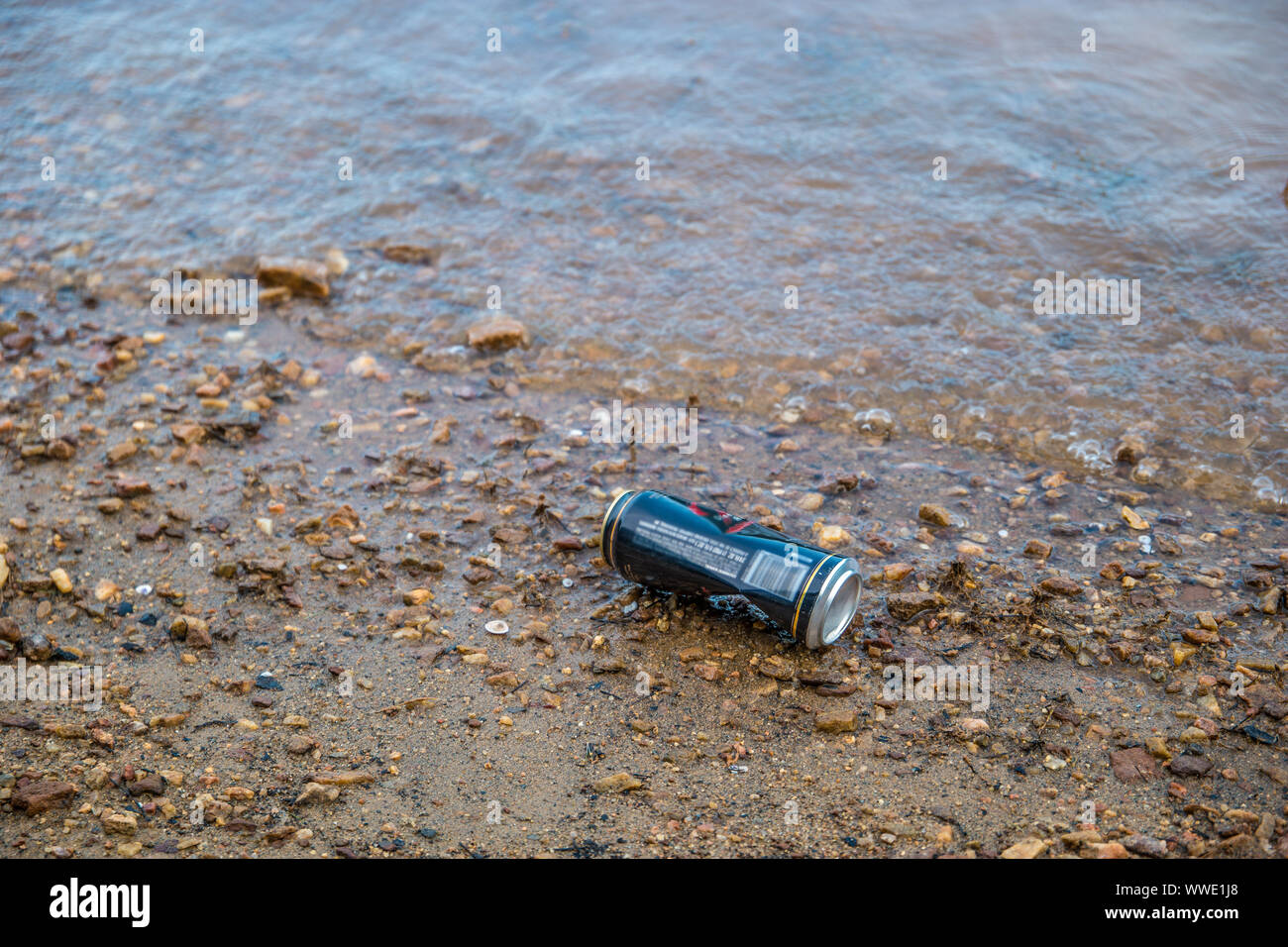 Une boîte de boisson jetées d'un dumping sur la plage près de l'eau au bord du lac en été, la pollution de l'environnement libre Banque D'Images