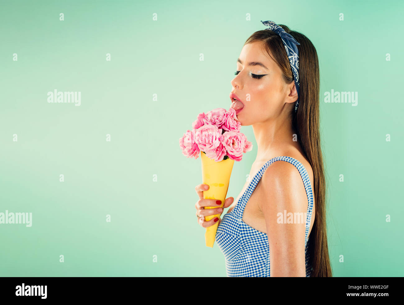Pinup girl avec mode de cheveux. pin up femme avec bouquet de fleurs. maquillage. Fleuriste. L'été. retro woman eating ice cream de fleurs. jolie fille dans Banque D'Images