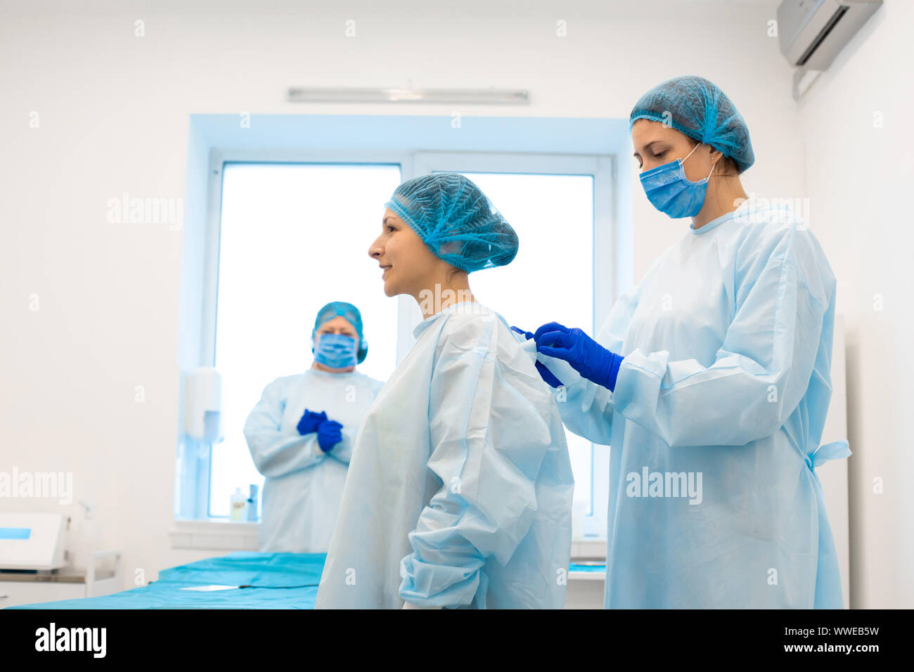L'infirmière met le patient dans une blouse stérile pour l'opération. L'élimination des taupes dans une clinique privée. Banque D'Images