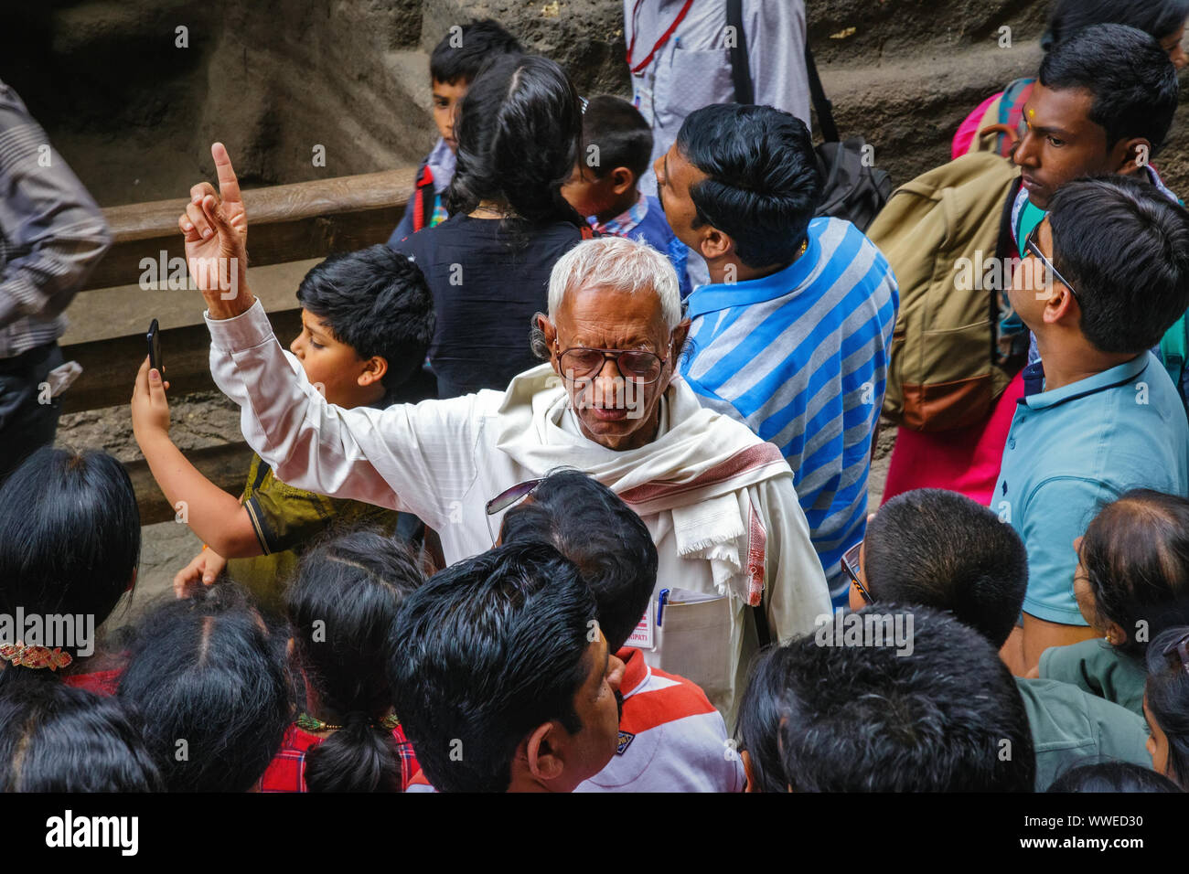 Ellora, Maharashtra, Inde - 15 janvier 2018 : Un homme âgé effectue un guide d'excursion. Un groupe de visiteurs sont à l'écoute de l'information historique Banque D'Images