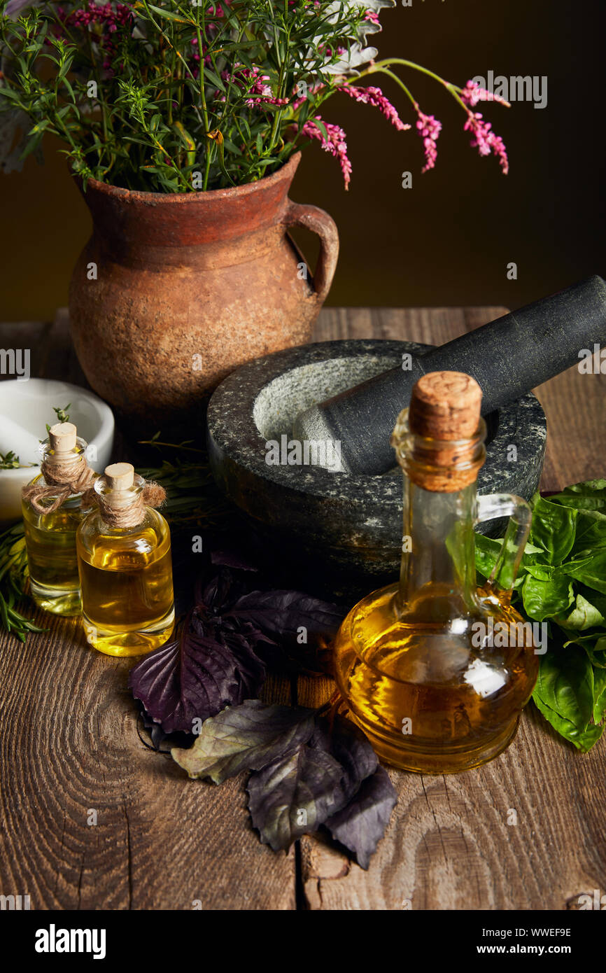 Mortier avec pilon, bouteilles d'huile et de l'argile vase avec fleurs fraîches sur la surface en bois isolé sur black Banque D'Images