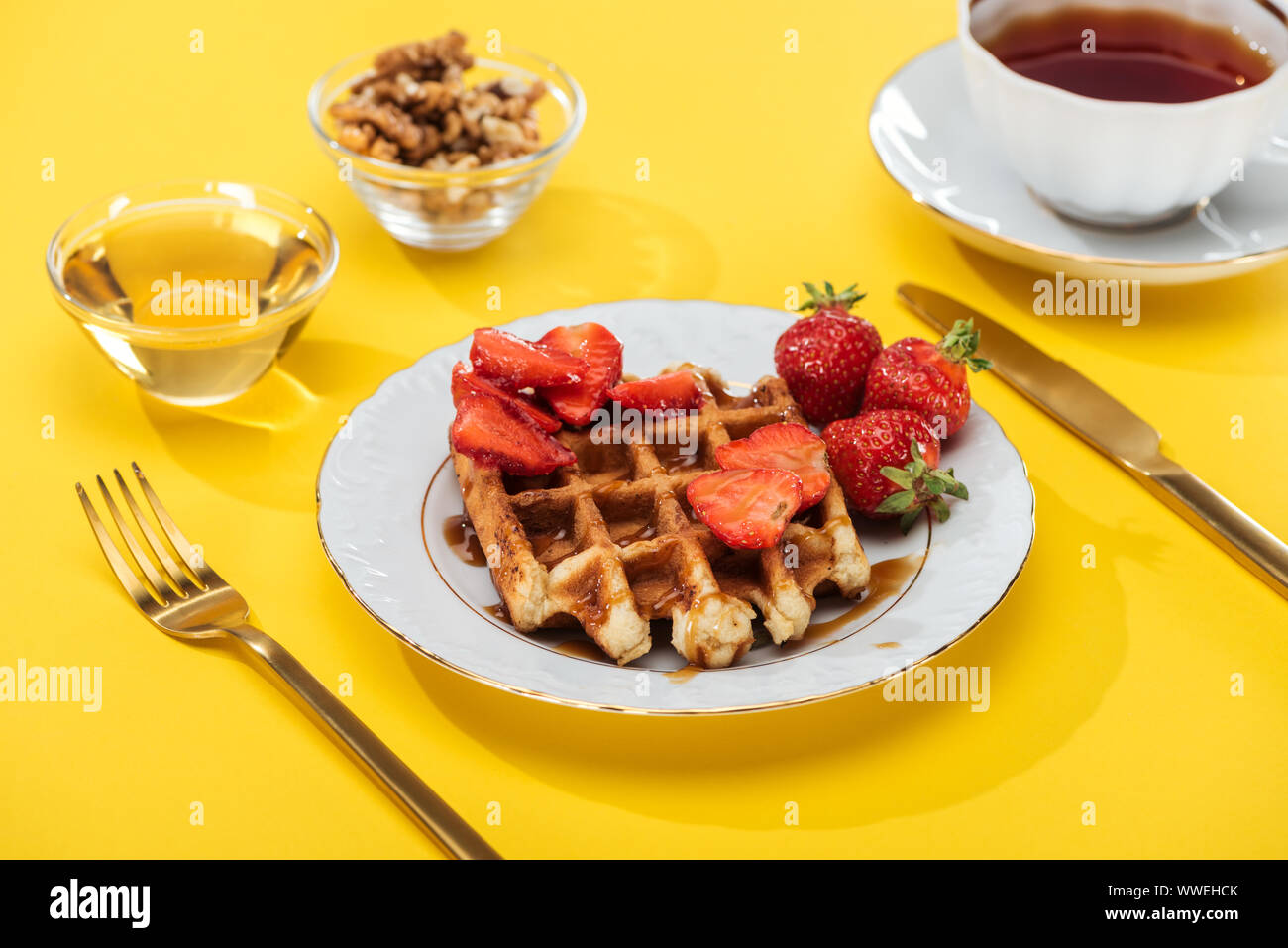 Petit-déjeuner servi avec waffle, fraises, miel, noix et d'un plateau sur jaune Banque D'Images