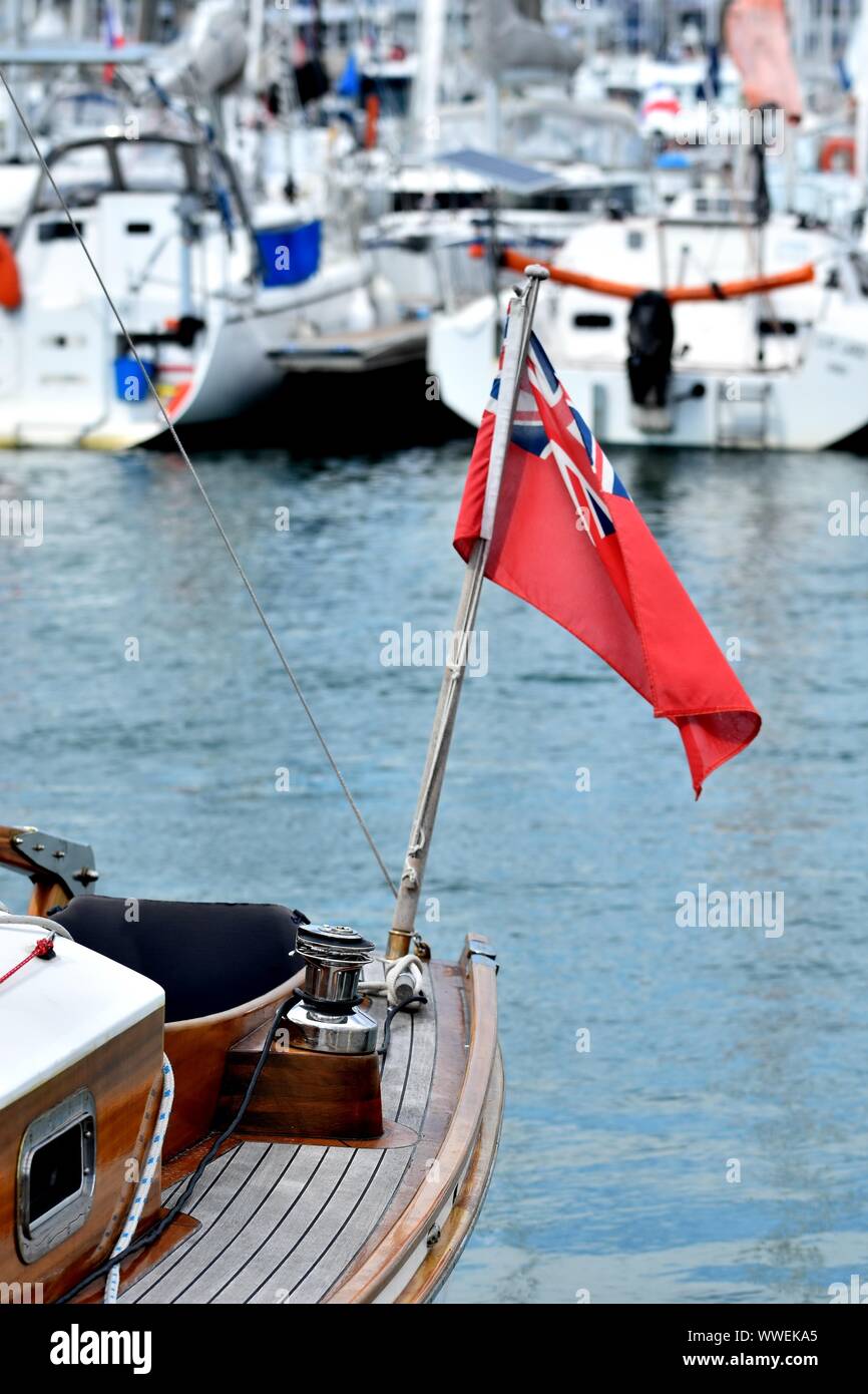 Voilier en bois amarré à la marina. Détails de classic beau yacht à voile avec pont en teck, treuil et drapeau britannique sur l'arrière-plan flou Banque D'Images