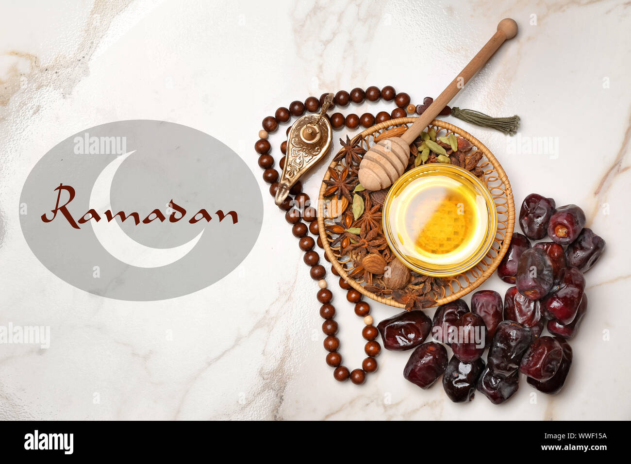 Lampe musulmane, dates, miel, tasbih et mot RAMADAN sur fond clair Banque D'Images