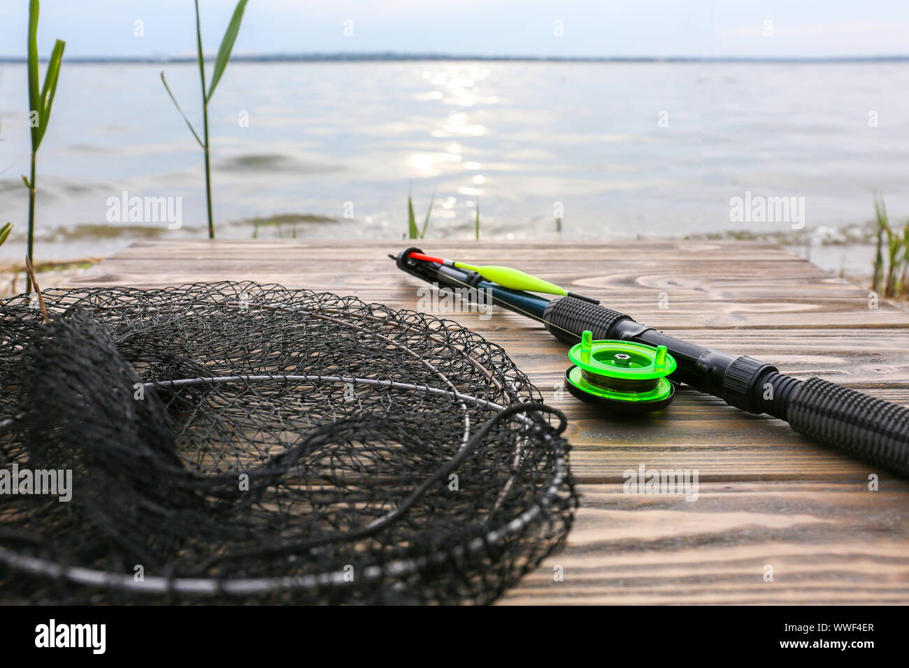Canne à pêche moderne avec net sur la jetée près de la rivière Banque D'Images
