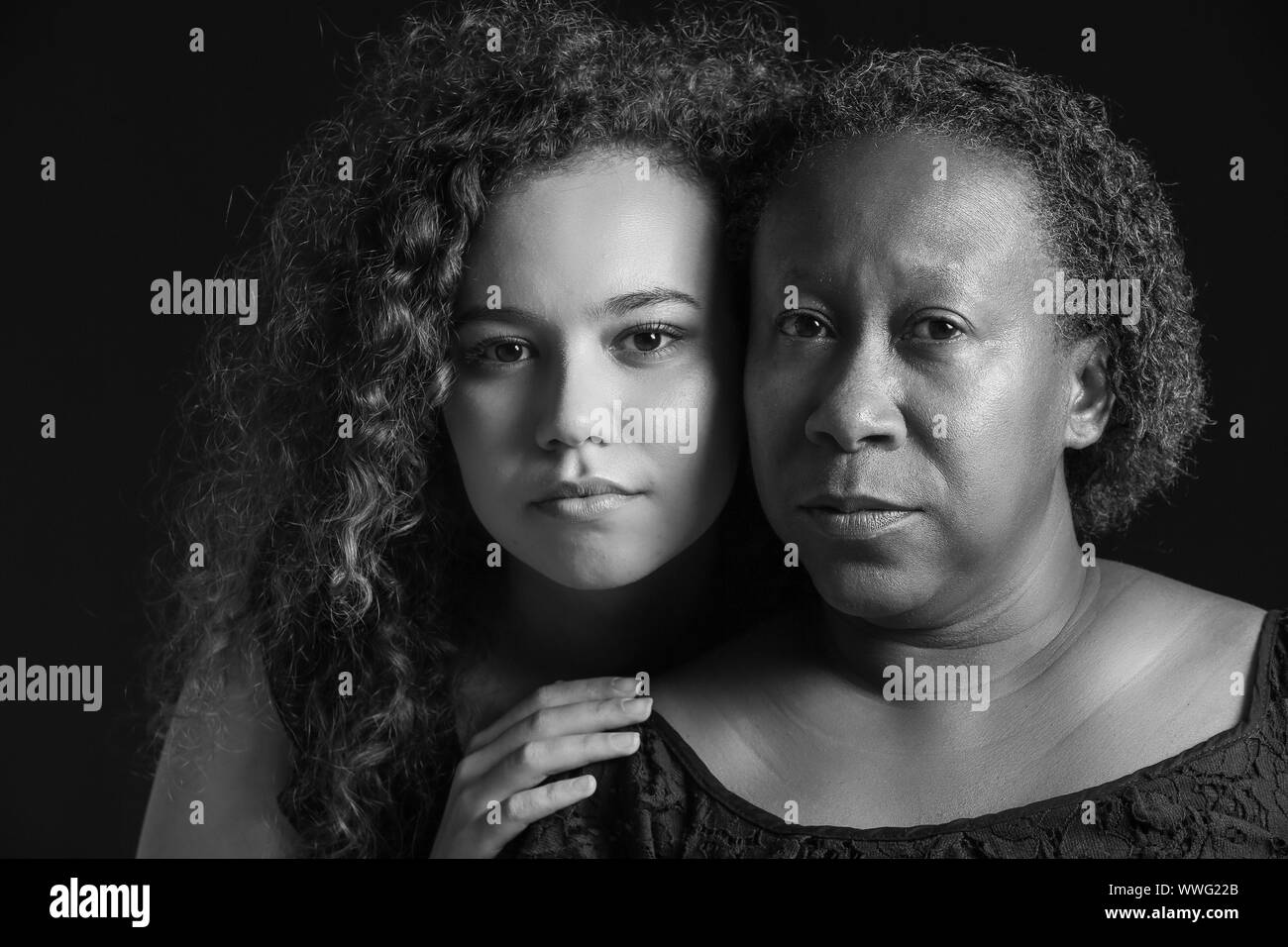 Le noir et blanc portrait de femme afro-américaine avec sa fille sur fond sombre Banque D'Images