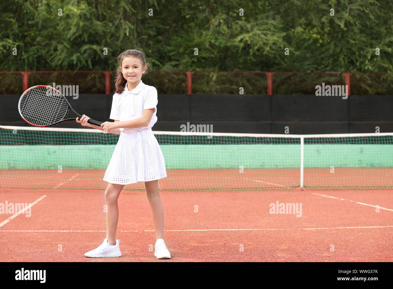 Petite fille jouant au tennis sur le court Banque D'Images