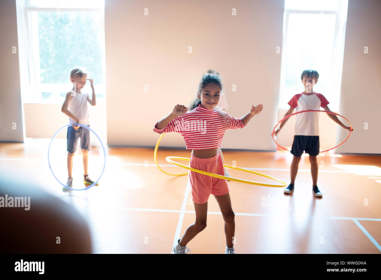 Jeune fille à la peau sombre sentiment incroyable tout en roulant le hula-hoop Banque D'Images