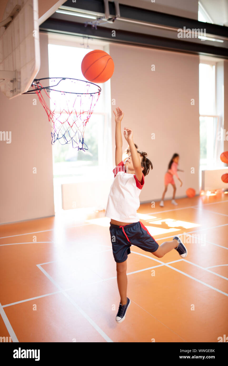 Garçon sautant de haut tandis que la formation et jouer au basket-ball Banque D'Images