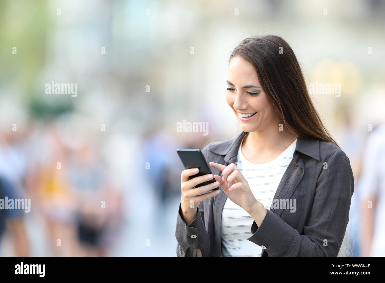 Heureux femme contrôle smart phone en ligne permanent contenu dans la rue Banque D'Images