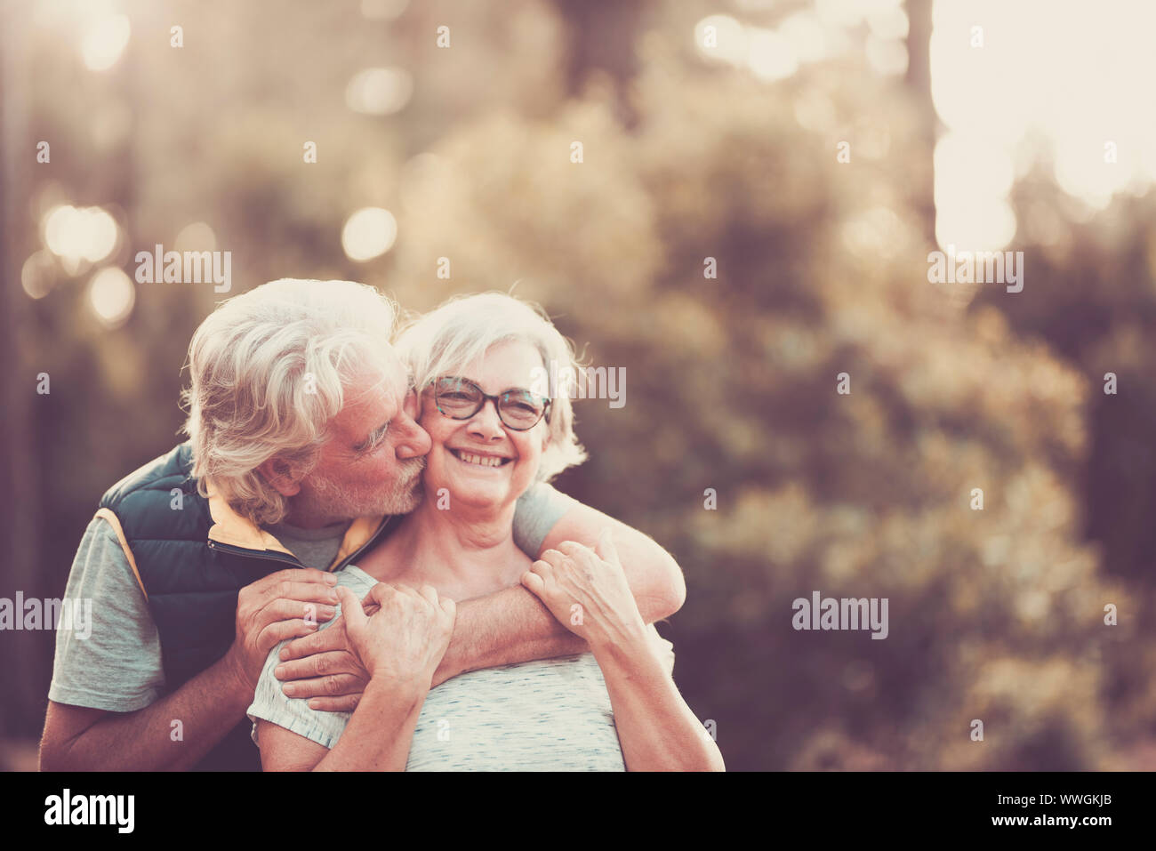 Couple d'heureux et joyeux les gens portrait hauts hug avec amour et sourire avec la forêt verte de flou artistique en arrière-plan - activité de loisirs de plein air pour Banque D'Images