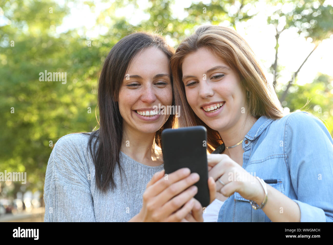 Vue avant portrait d'une femme adulte et adolescente contrôle smart phone ensemble dans un parc Banque D'Images