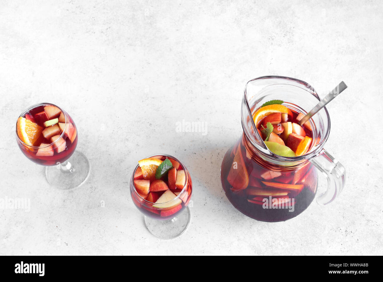 Vin rouge sangria ou punch aux fruits et de la glace dans les verres et pichet. Des fruits rafraîchissante sangria sur fond blanc, copie de l'espace. Banque D'Images