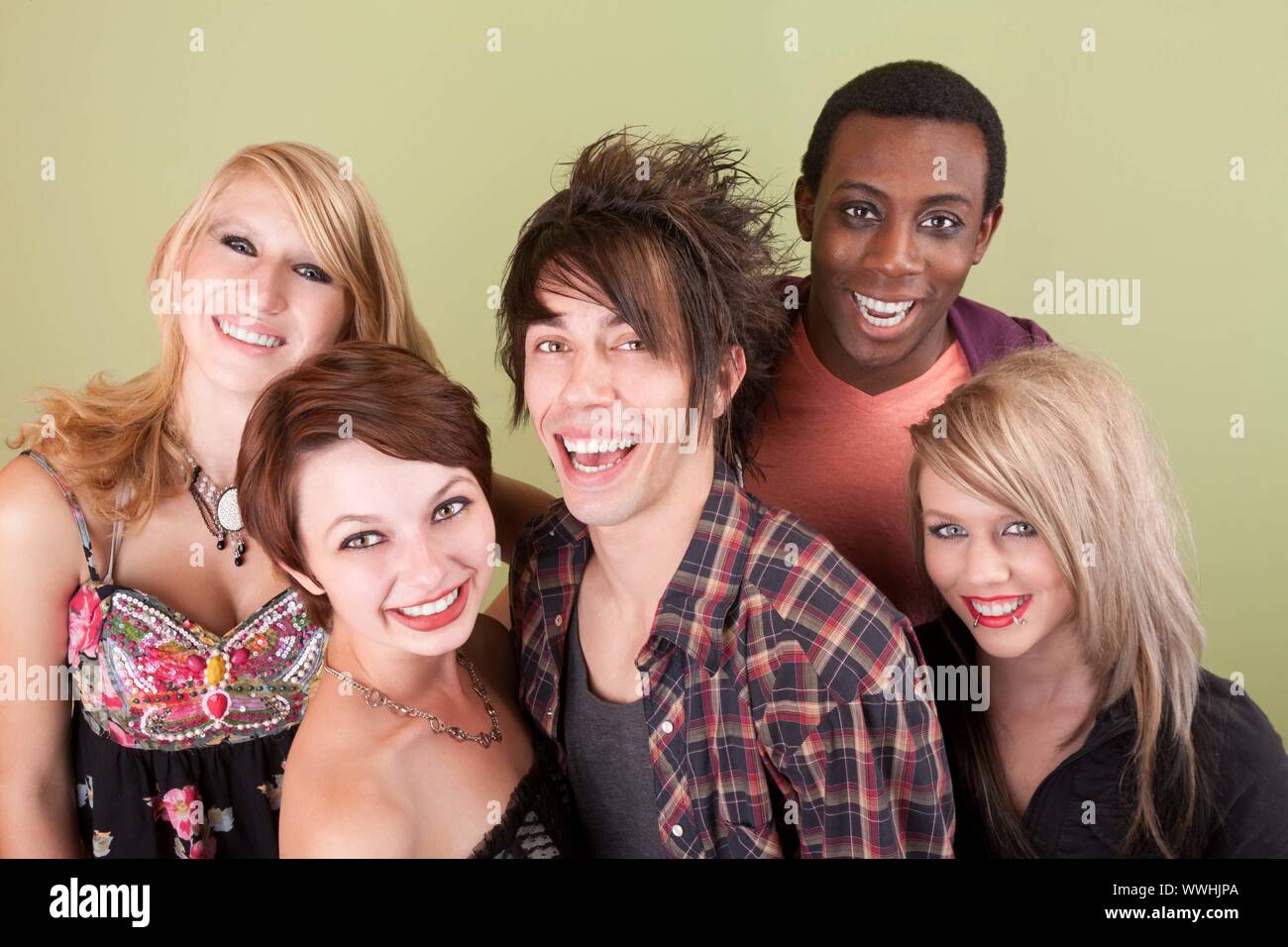 Cinq adolescents habillés urbain rire vers la caméra en face d'un green studio mur. Banque D'Images
