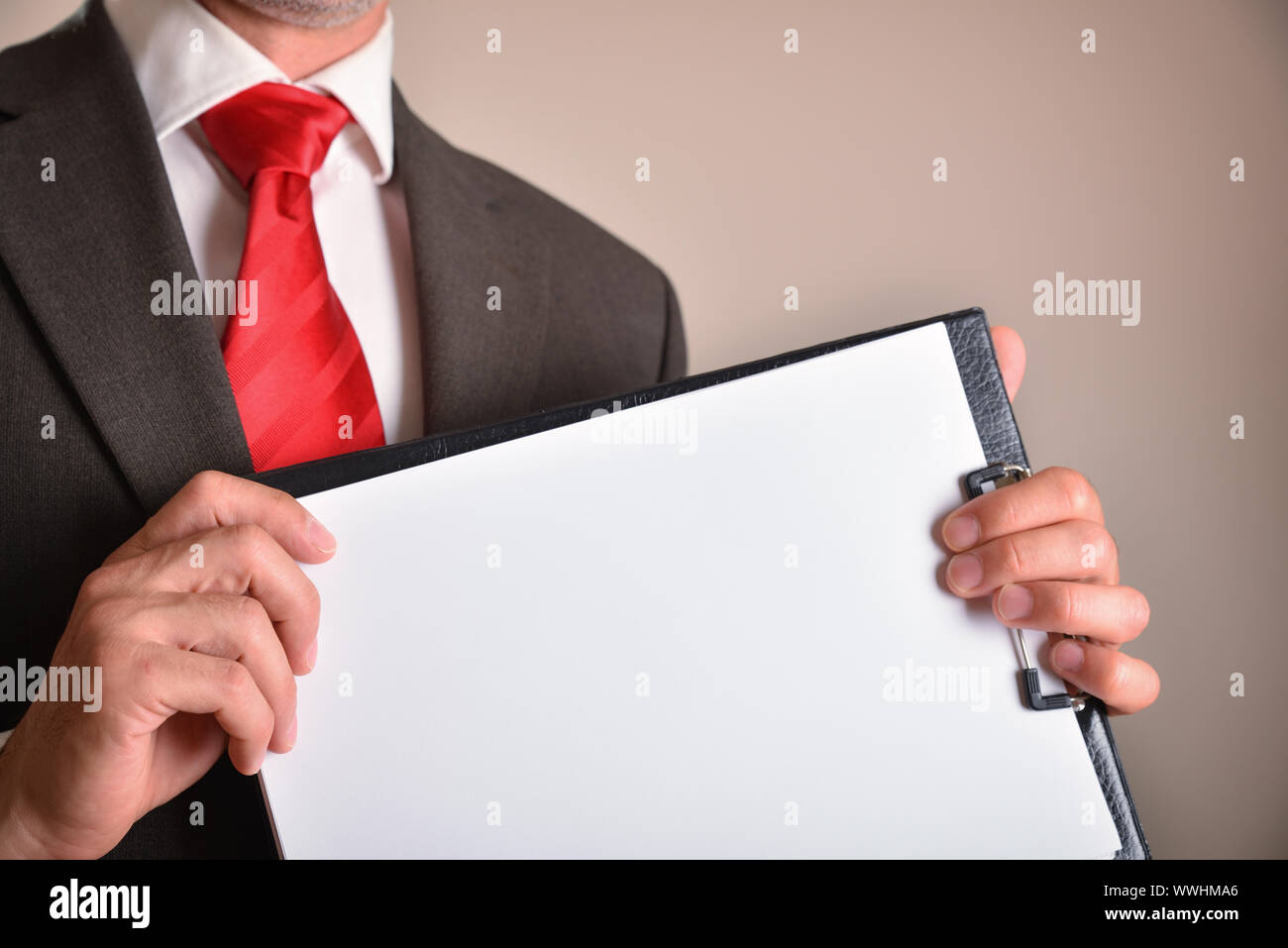 L'homme en costume avec cravate rouge montrant un dossier avec des feuilles  vierges avec brown isolated background. Composition horizontale. Vue de  face Photo Stock - Alamy