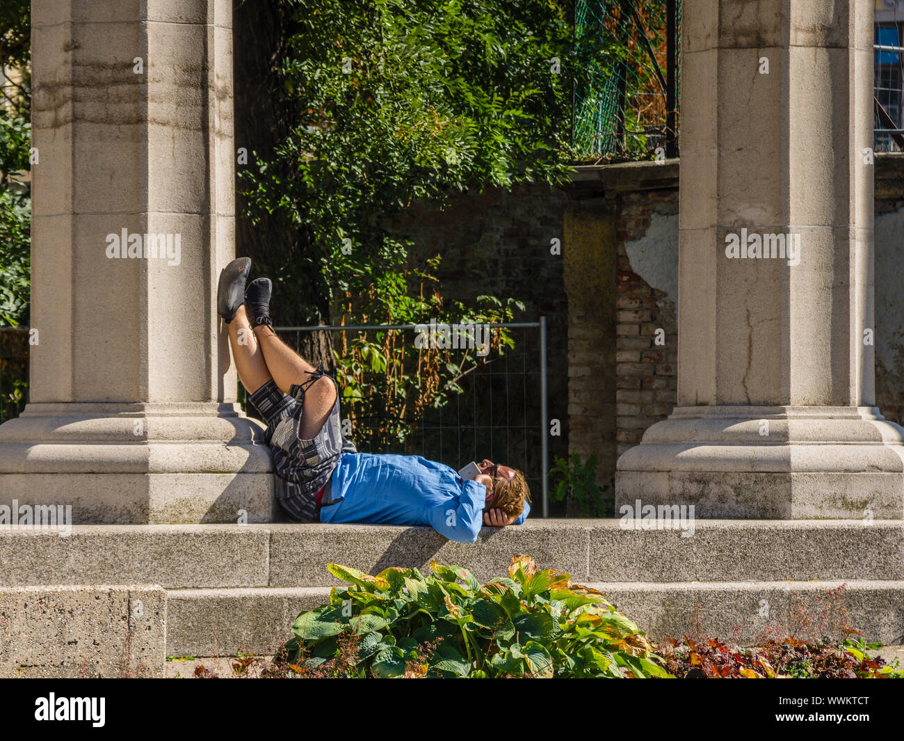 L'homme allongé sur le dos au soleil faisant appel téléphonique. Banque D'Images