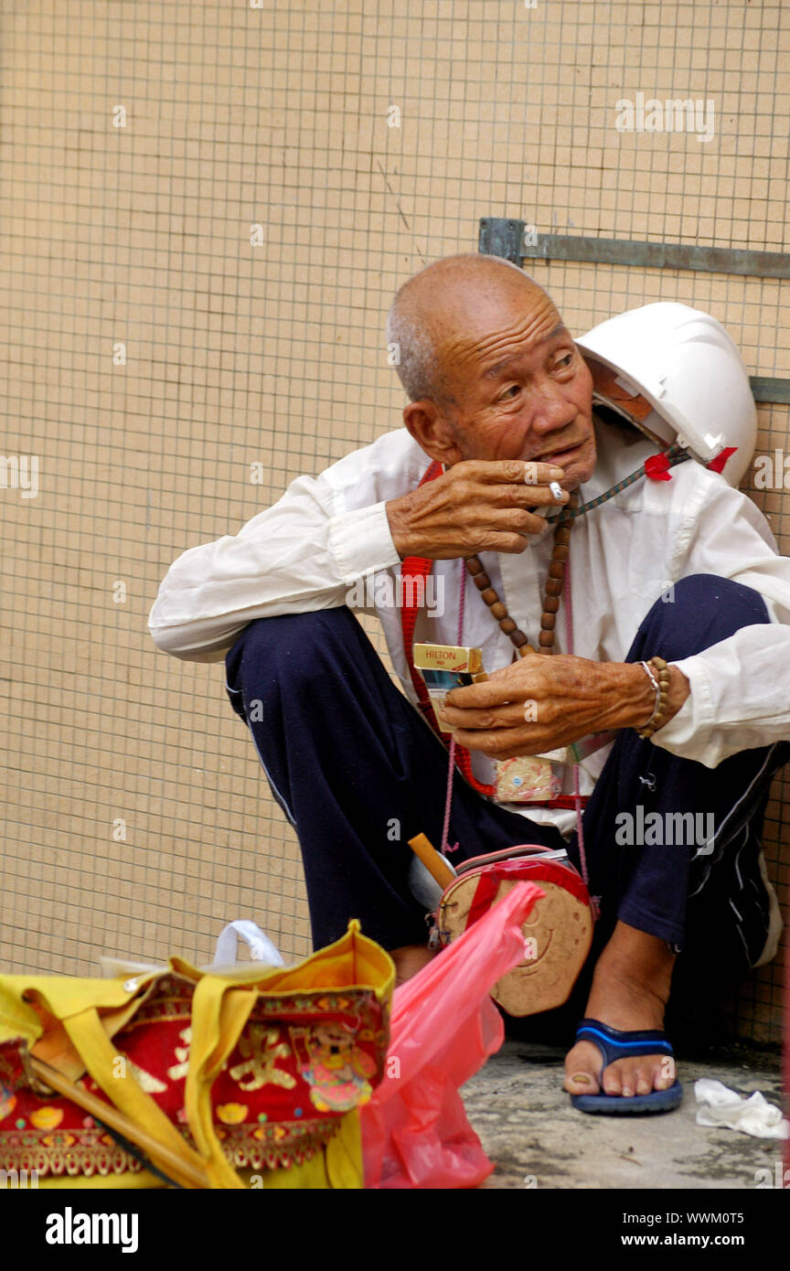 Un vieil homme qui fume dans la rue à Hong Kong Banque D'Images