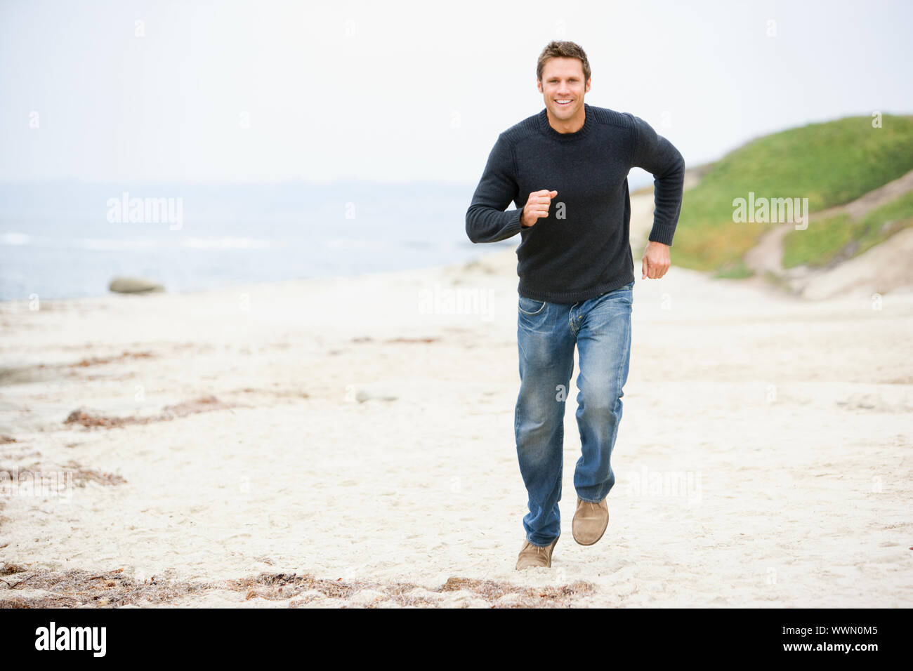 Man running at beach smiling Banque D'Images