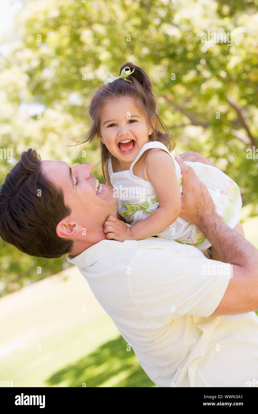 Père holding daughter outdoors smiling Banque D'Images