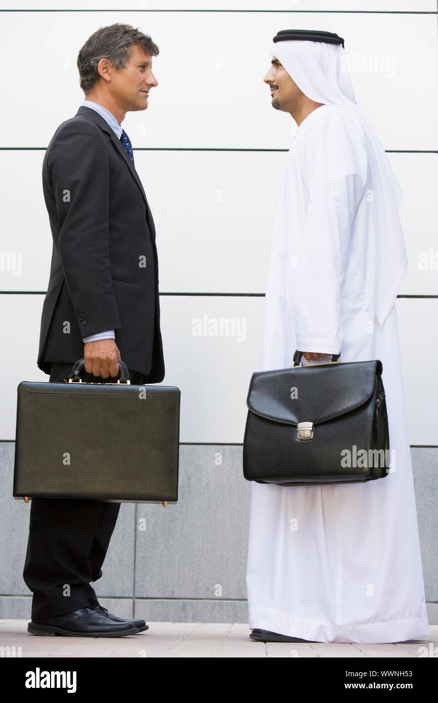 Deux businesspeople standing en plein air avec porte-documents smiling Banque D'Images
