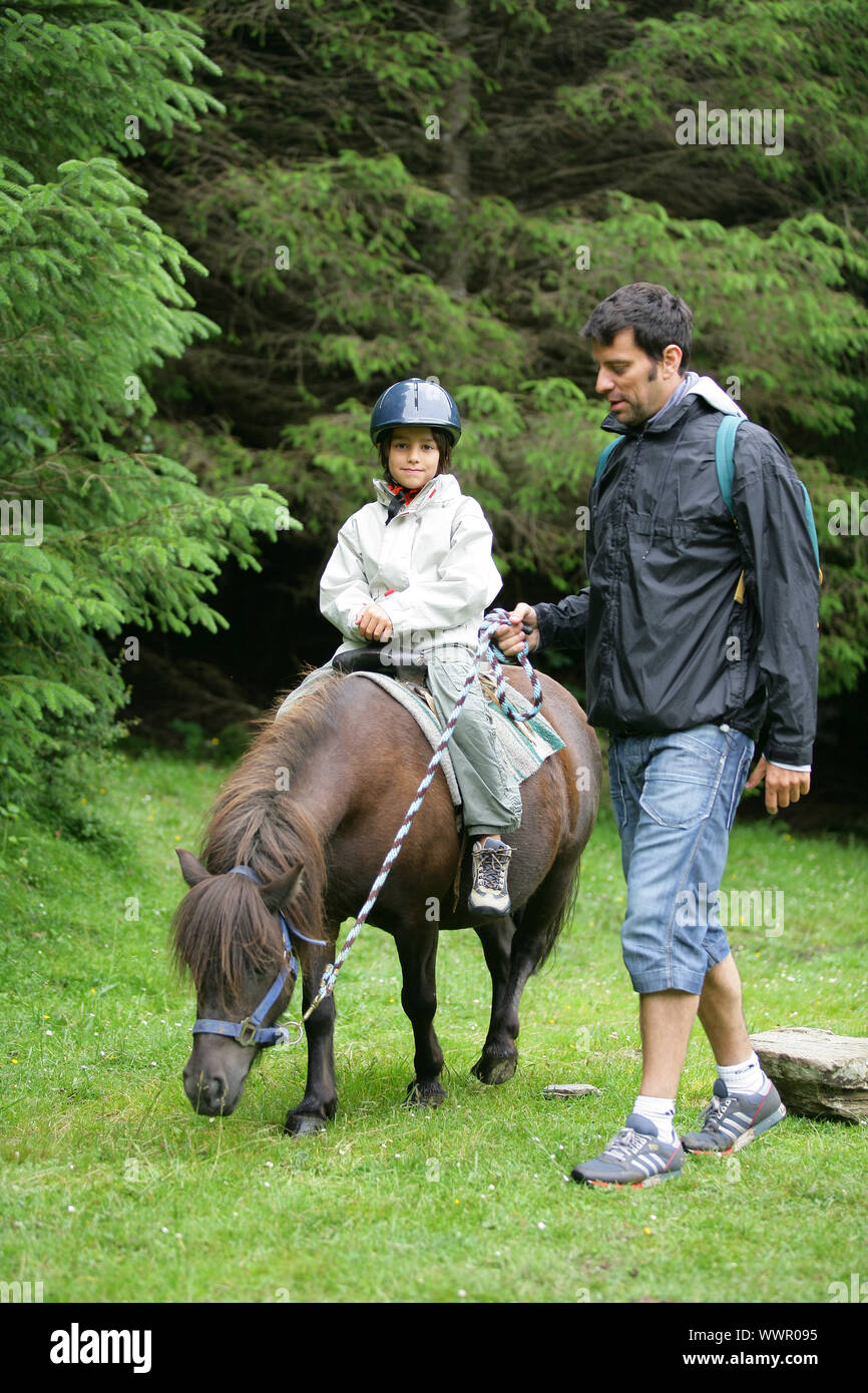 Père d'aider sa fille monter un poney Banque D'Images