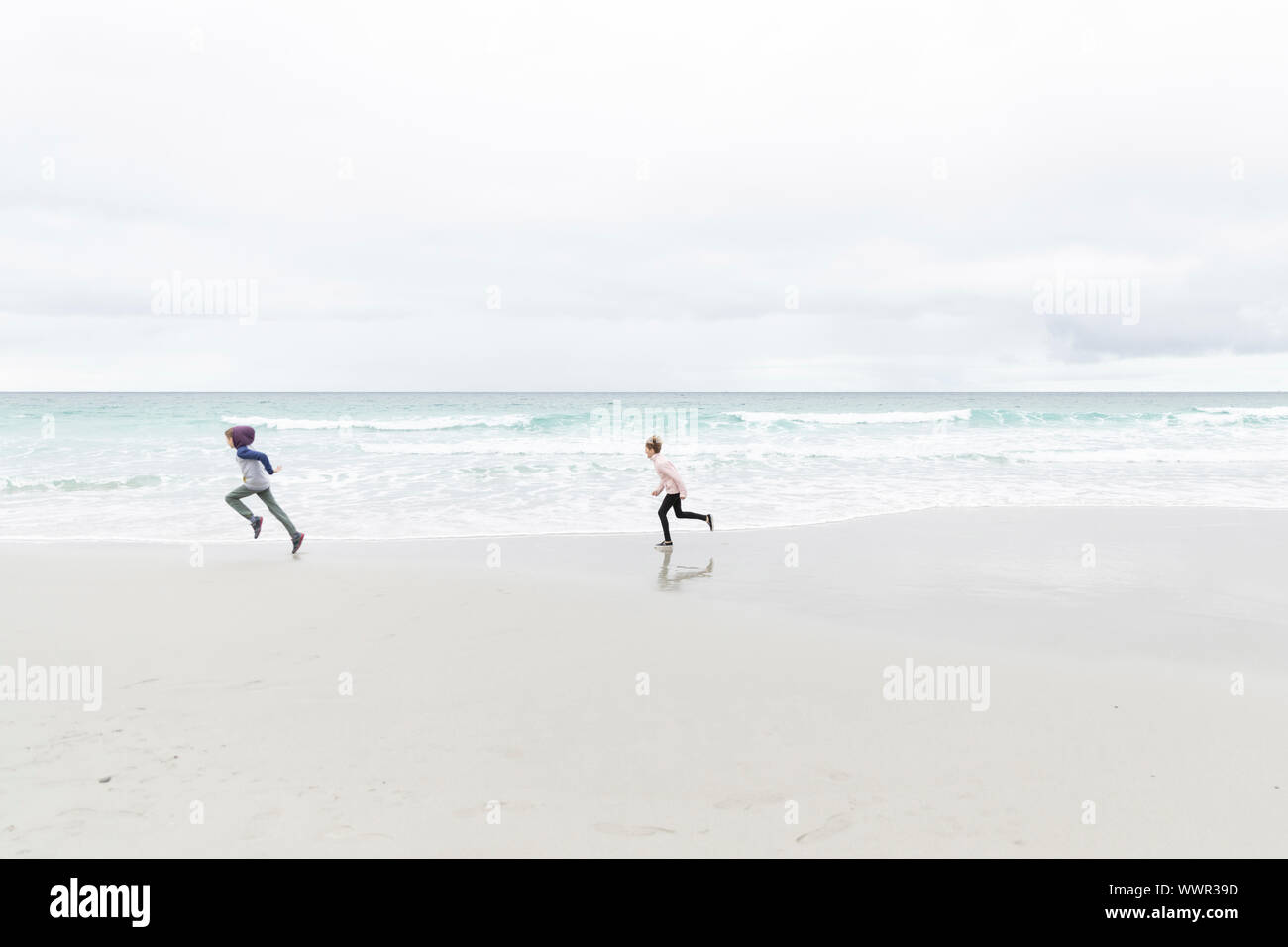 Jeune garçon et fille courir sur la plage de Carmel, Californie Banque D'Images
