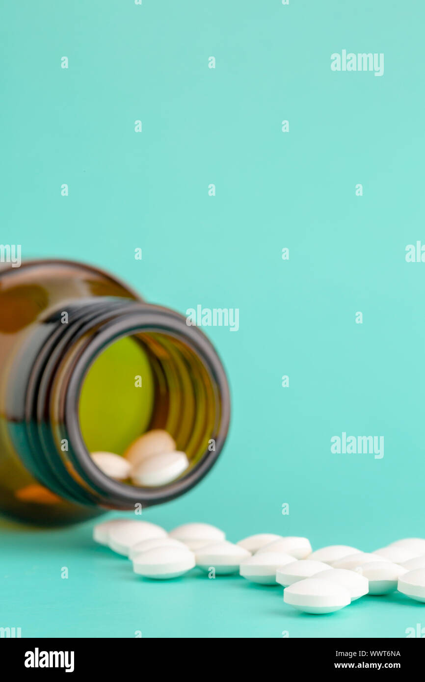 Comprimé rond blanc dispersés en face du verre bouteille de pilules Banque D'Images