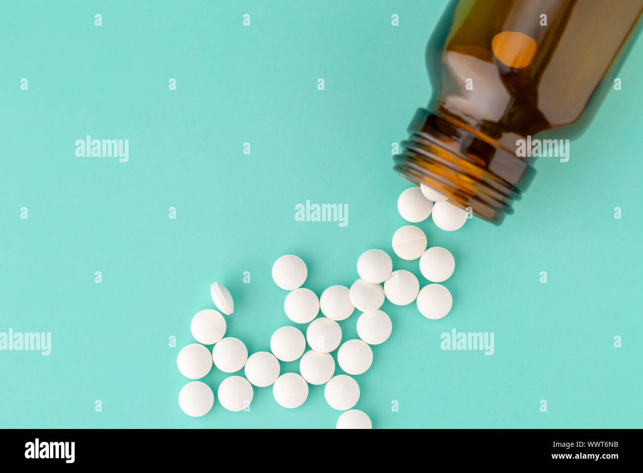 Comprimé rond blanc dispersés en face du verre bouteille de pilules Banque D'Images