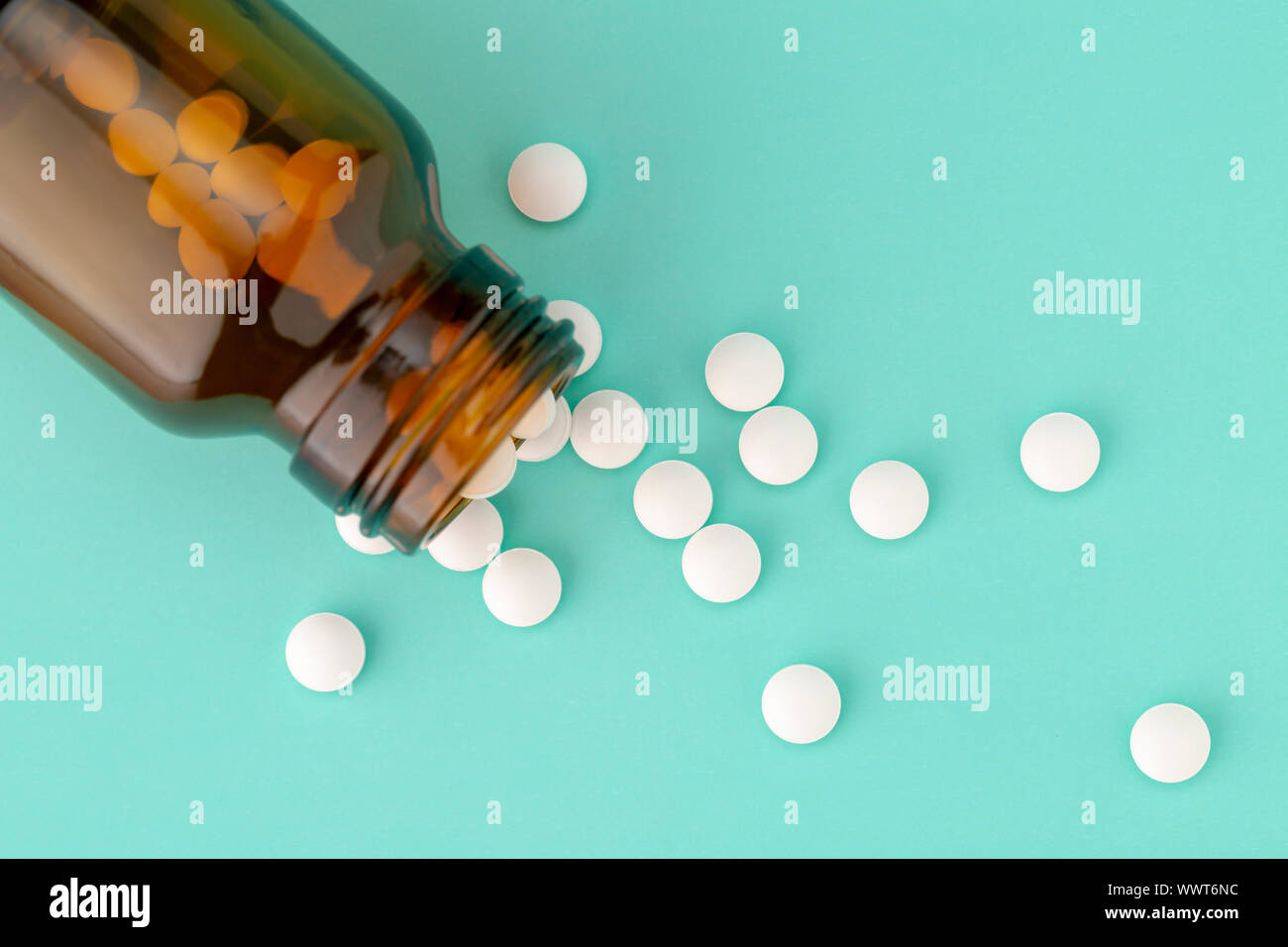 Comprimé rond blanc dispersés en face du verre bouteille de pilules Banque D'Images
