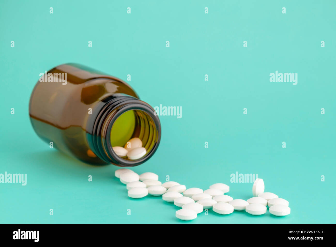 Comprimé rond blanc dispersés en face du verre bouteille de pilules Banque D'Images
