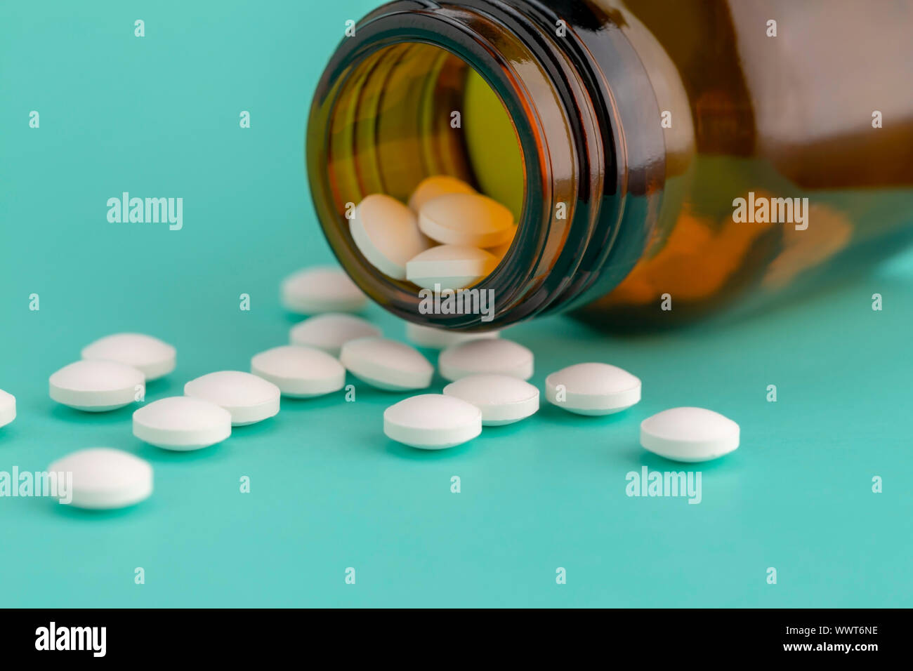 Comprimé rond blanc dispersés en face du verre bouteille de pilules Banque D'Images