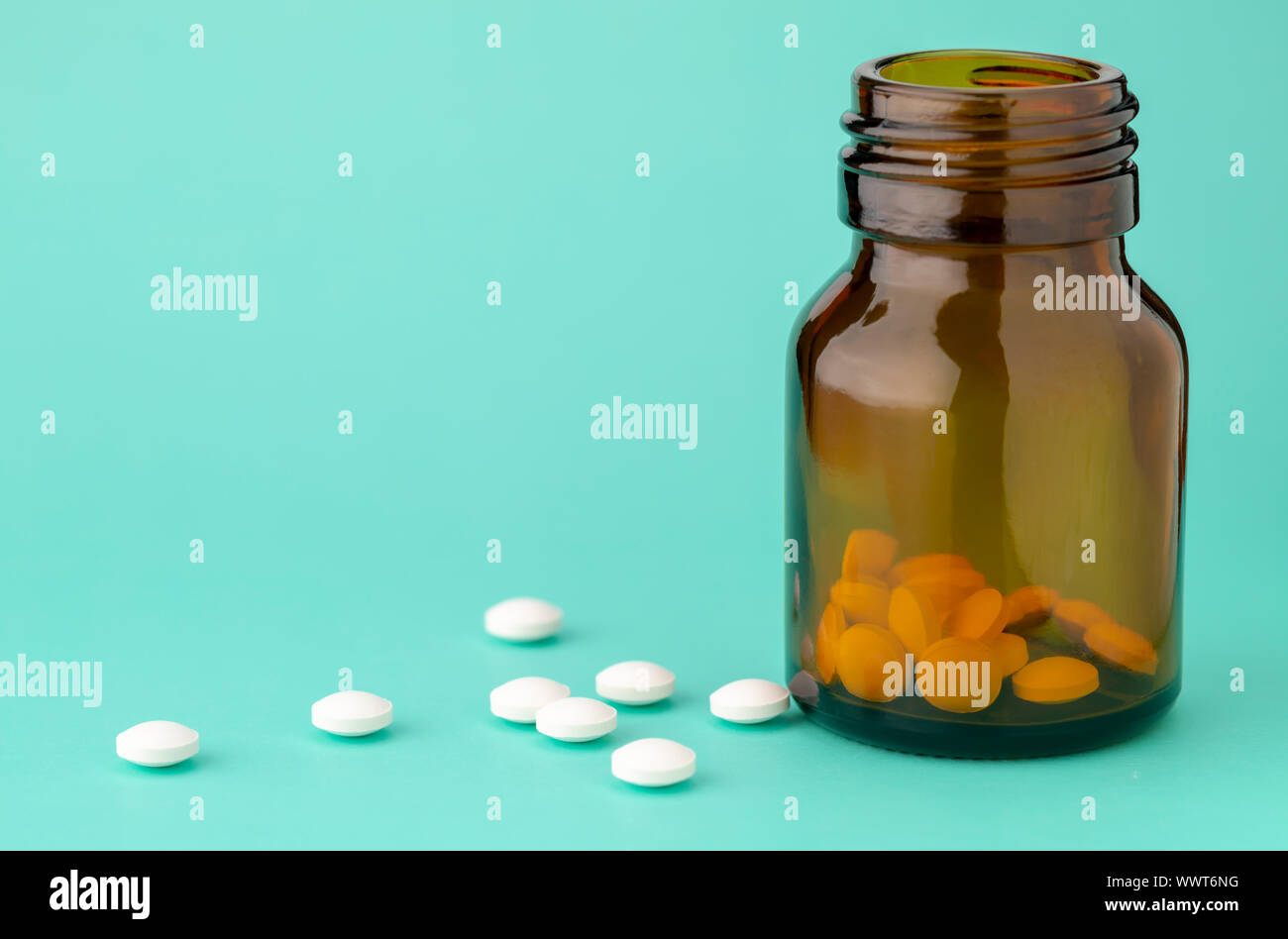 Comprimé rond blanc dispersés en face du verre bouteille de pilules Banque D'Images