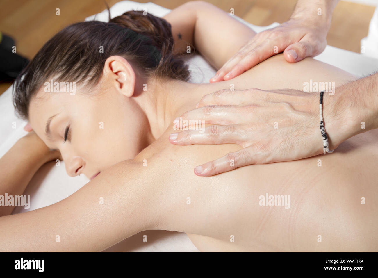 Massage et relaxation, beautiful brunette woman détente sur une civière, recevant un massage thérapeutique de mains d'une professe Banque D'Images