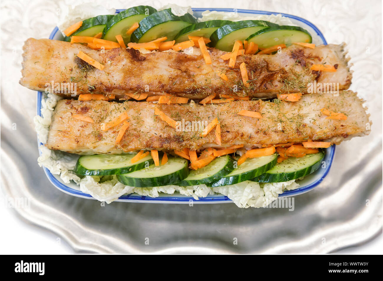 Le poisson frit avec des légumes dans un plat de céramique. Banque D'Images